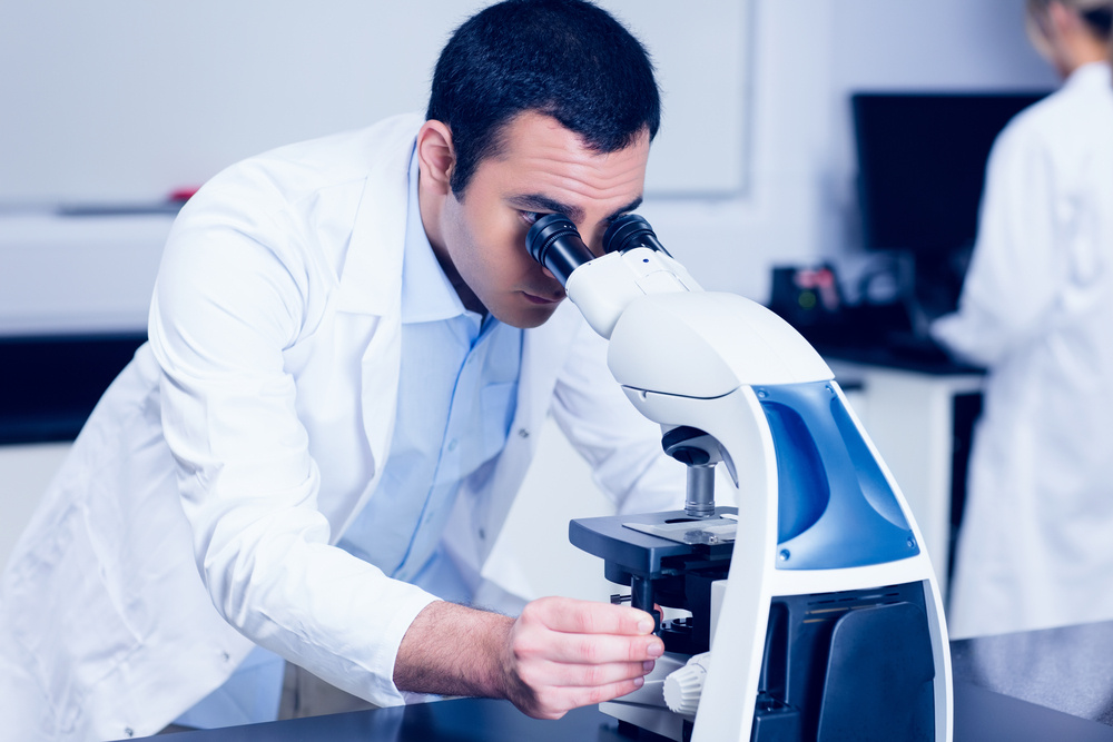 Science student looking through microscope at the university