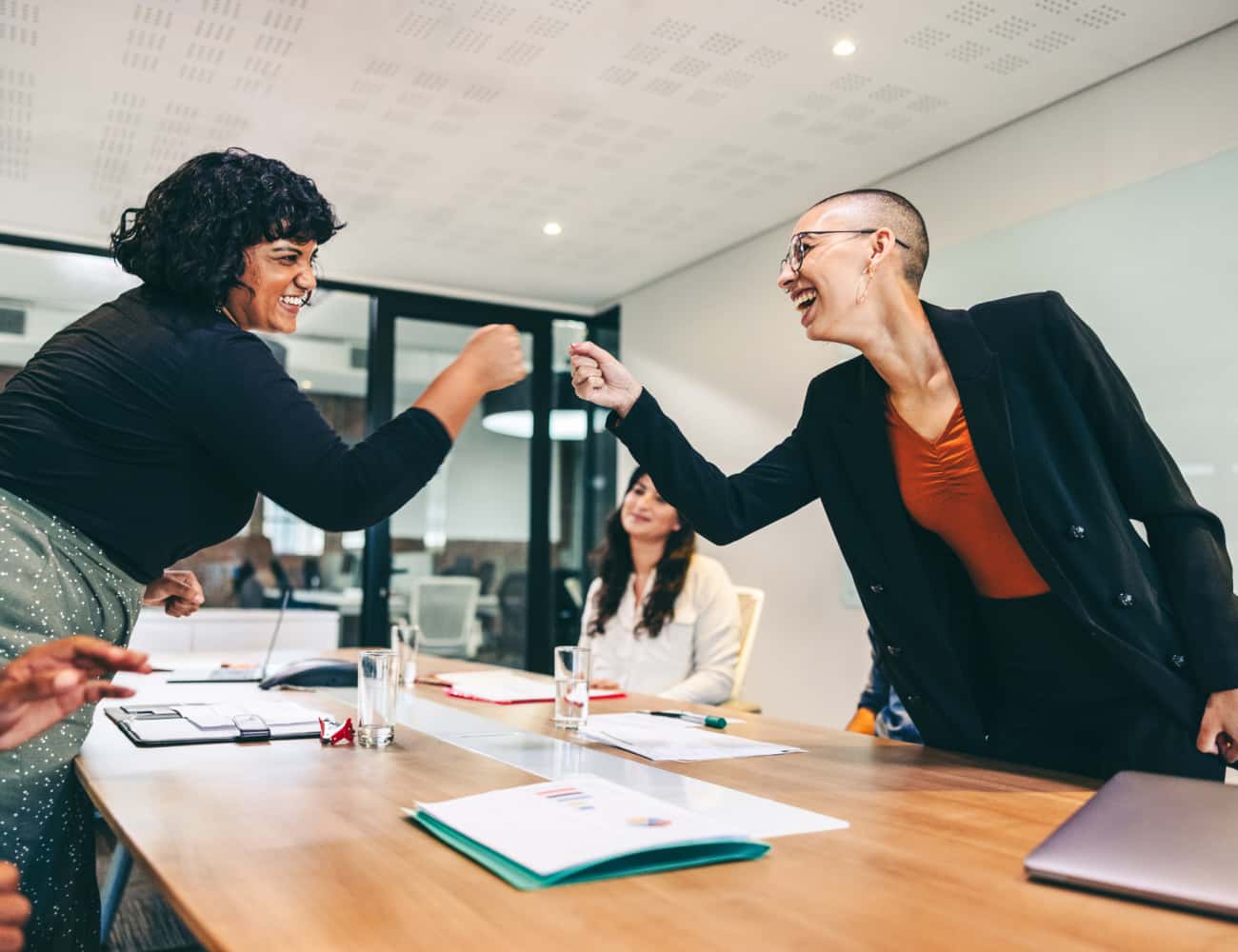 two-women-fist-bumping-in-a-meeting-650x500