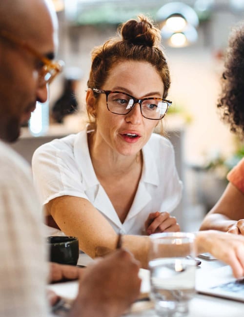 woman pointing out information on a screen to her coworkers